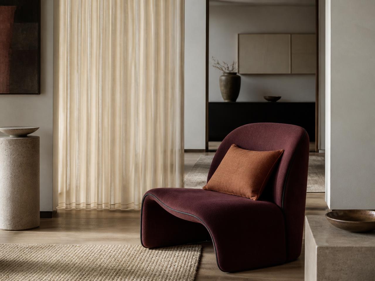 Burgundy upholstered lounge chair with ivory curtains and a copper cushion designed as a coordinated NineWaves furnishing concept